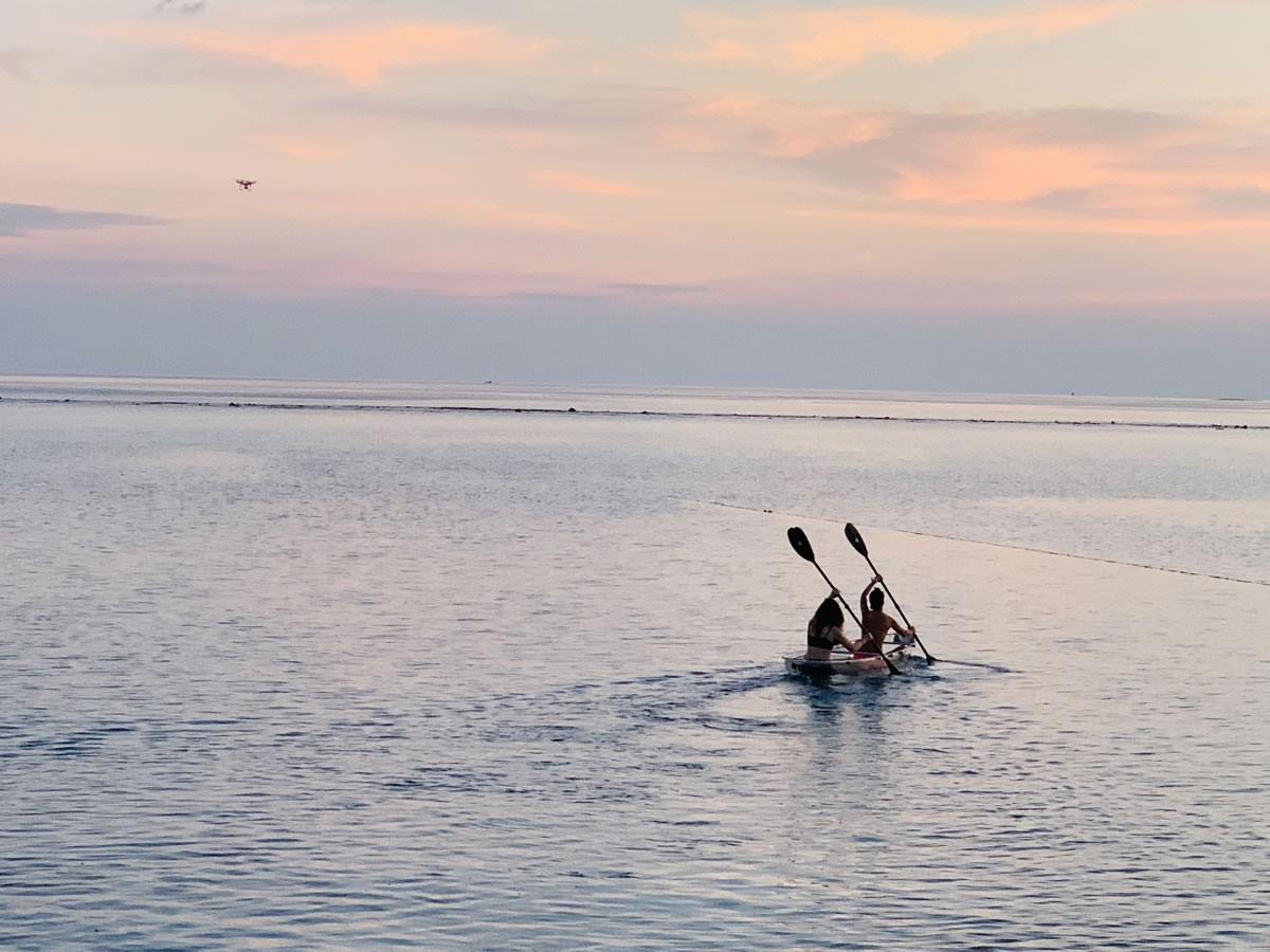 旅客在馬爾地夫夕陽海面划獨木舟