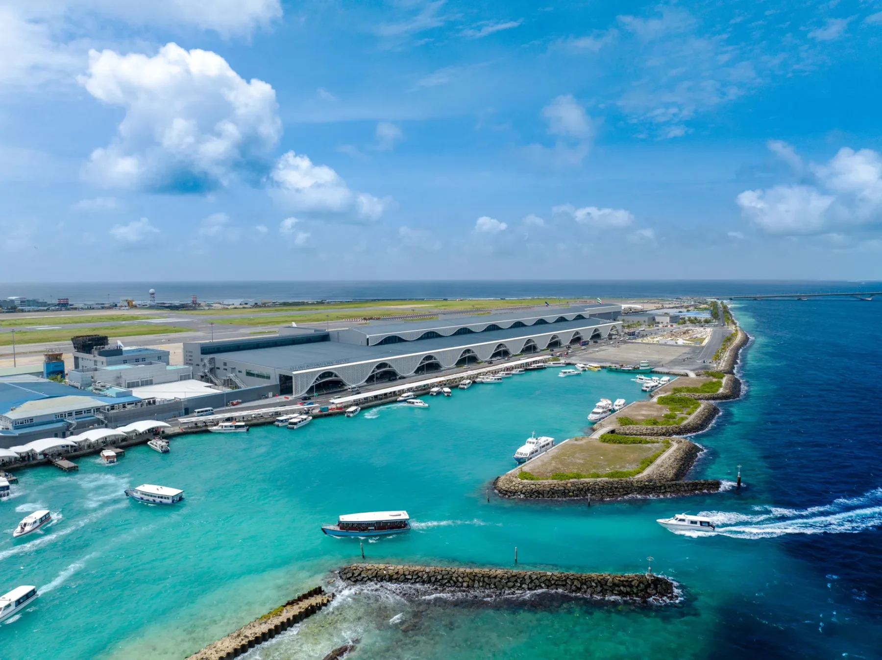 馬列維拉納國際機場第一航廈空拍：面海一側的白色扇形拱廊、快艇碼頭與後方跑道
