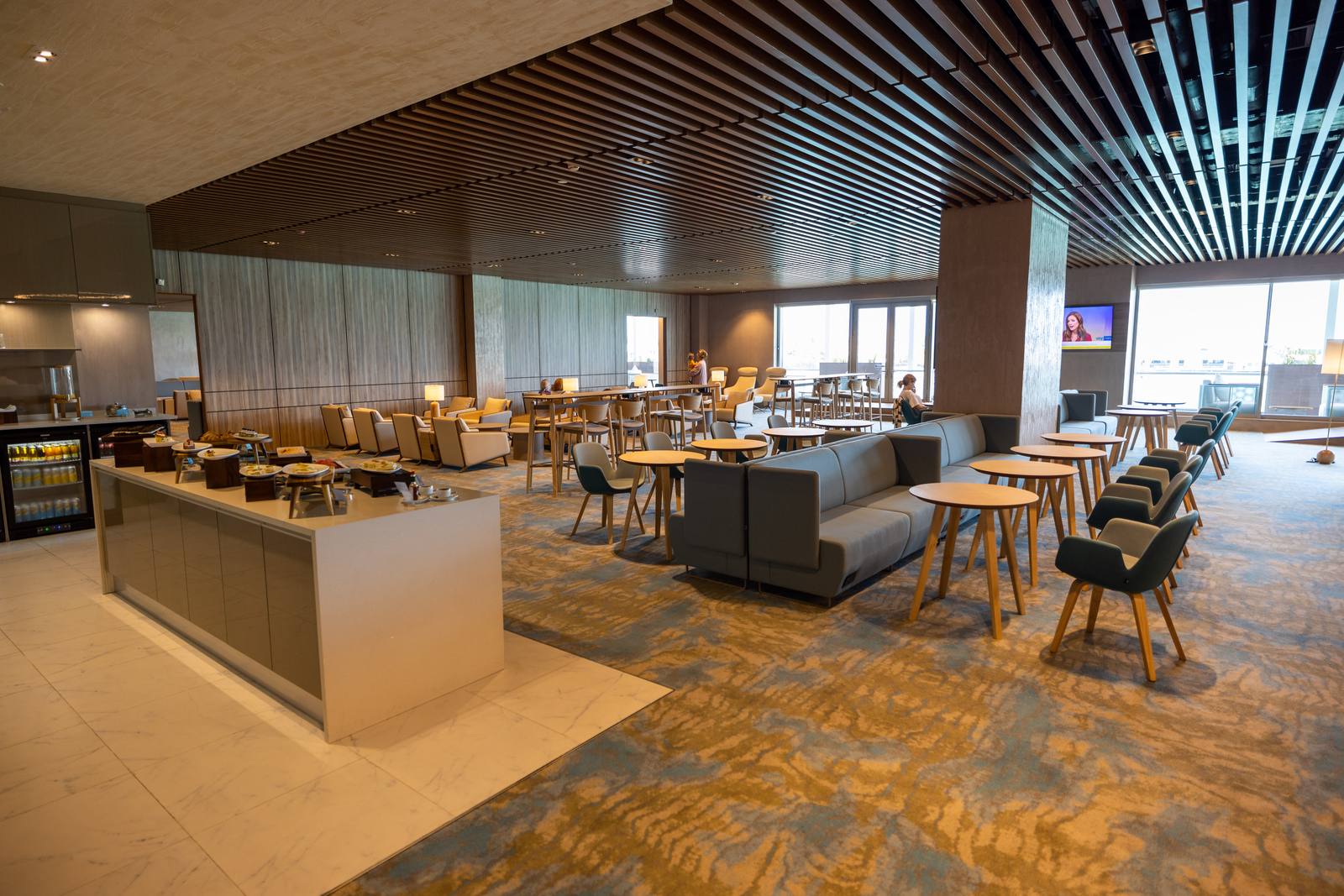 Vilu Business Lounge 的自助餐台、沙發與高腳桌,窗外是停機坪